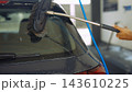 Hand cleaning car windshield with brush and water 143610225