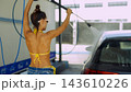Woman washing car with pressure sprayer at car wash 143610226