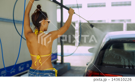 Woman washing car with pressure sprayer at car wash 143610226