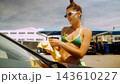 Young woman cleaning car at sunny seaside location 143610227