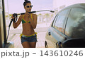 Woman washing car with pressure washer at outdoor station 143610246