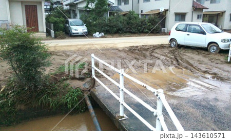 大雨被害で泥や土砂が流れ込んだ住宅地の道路と川1 大雨被害で泥や土砂が流れ込んだ住宅地の道路と川1 143610571