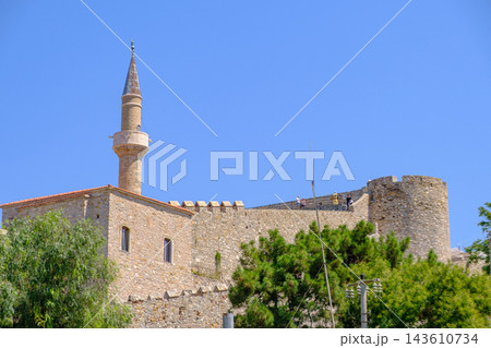 Historic Cesme Castle and Mosque Minaret Against Blue Sky 143610734