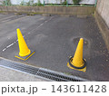 月極駐車場の入口に並べられた黄色いカラーコーンと車止め 143611428
