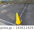 アスファルト駐車場の区画線と手前に置かれた黄色い三角コーン 143611429