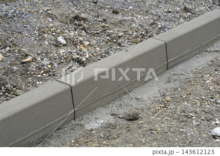 Concrete kerb stone installation on a construction site 143612123