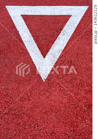 White yield triangle road marking on red asphalt White yield triangle road marking on red asphalt 143612129
