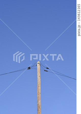 Wooden utility pole with electric wires under blue sky Wooden utility pole with electric wires under blue sky 143612165