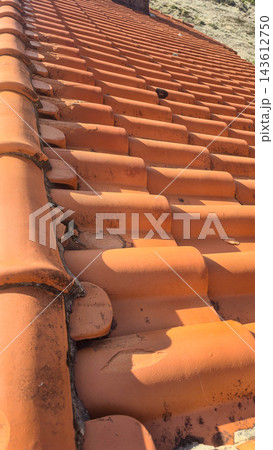 Traditional terracotta roof tiles cover a residential building in northern Portugal. Concepts: Portuguese architecture, Mediterranean roofing, construction materials, property maintenance. Traditional terracotta roof tiles cover a residential building in northern Portugal. Concepts: Portuguese architecture, Mediterranean roofing, construction materials, property maintenance. 143612750