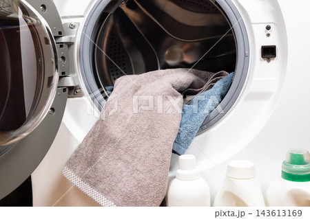 Loading laundry into washing machine with detergent Loading laundry into washing machine with detergent 143613169