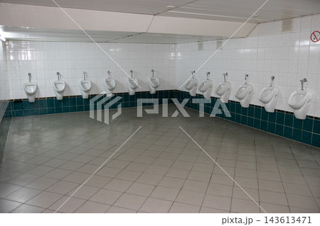 Multiple urinals in a public restroom with clean tiles and plenty of space Multiple urinals in a public restroom with clean tiles and plenty of space 143613471