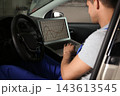 Mechanic with laptop doing car diagnostic at automobile repair shop 143613545