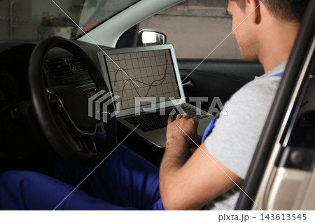 Mechanic with laptop doing car diagnostic at automobile repair shop 143613545