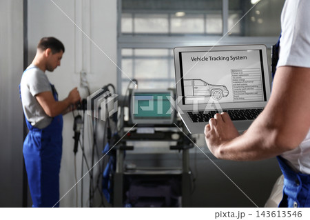 Mechanic with laptop doing car diagnostic at automobile repair shop, closeup. Space for text 143613546