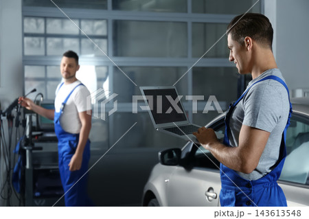 Mechanic with laptop doing car diagnostic at automobile repair shop. Space for text 143613548