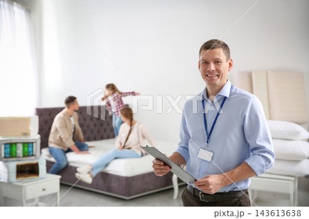 Happy salesman and his clients in mattress store Happy salesman and his clients in mattress store 143613638