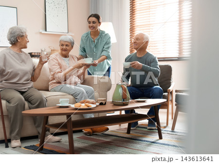 Young woman taking care of elderly people in living room 143613641