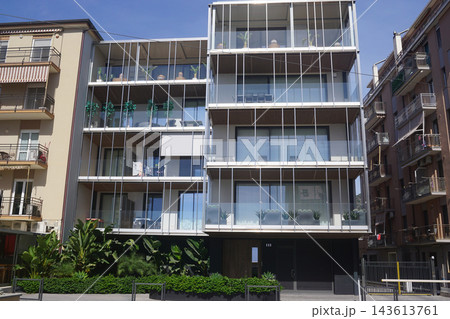 Modern four-story apartment building featuring panoramic balconies, floor-to-ceiling windows, lush greenery, and contemporary architectural design in a stylish residential setting. 143613761