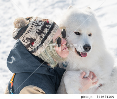 Portrait of a Smiling woman holding fluffy samoyed dog in snowy winter park. Portrait of a Smiling woman holding fluffy samoyed dog in snowy winter park. 143614309
