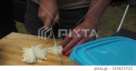 Woman Slicing White Onion on Wooden Cutting Board 143615722