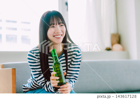 自宅のリビングでビールを飲む若い女性 自宅のリビングでビールを飲む若い女性 143617128