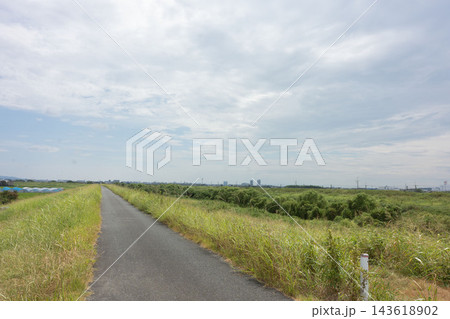 広い空と緑豊かな河川敷が広がる、のどかな郊外の風景 広い空と緑豊かな河川敷が広がる、のどかな郊外の風景 143618902