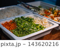 Neat trays hold carrots, spring onions, green beans, and diced cabbage beside steamed white rice, with metal tongs. Warm light highlights textures at a Maldives resort. 143620216