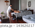 A spa therapist gives a back and shoulder massage in a wood floored room at a Maldives hotel spa. Soft gray linens, indoor plants, oil bowl, and a vanity with sink are visible. 143620217