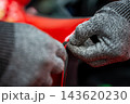 Gloved hands trim vinyl wrap along a glossy car panel edge in a luxury workshop. Shallow depth of field and controlled lighting emphasize precision and craft. 143620230