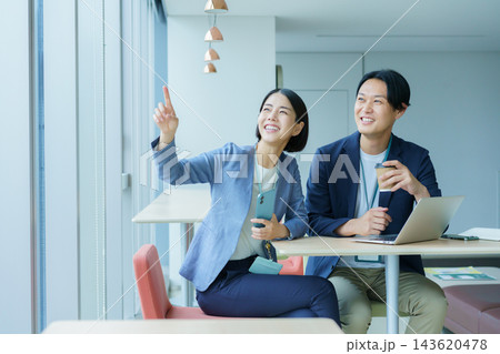 オフィスで会話する若い日本人男女2人 143620478