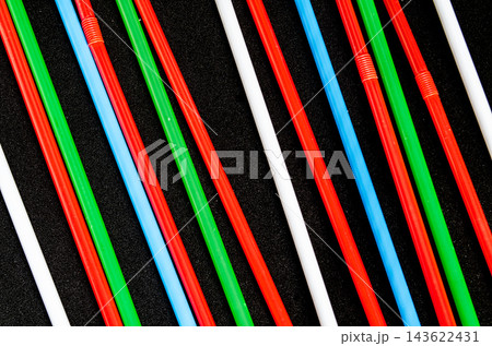 Colorful straws arranged in a pattern on a dark surface Colorful straws arranged in a pattern on a dark surface 143622431
