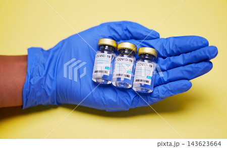 Hand, gloves and vaccine or vial in studio for wellness, healthcare and safety from disease. Medical worker, ppe and innovation by yellow background for protection, prevention and viral defence Hand, gloves and vaccine or vial in studio for wellness, healthcare and safety from disease. Medical worker, ppe and innovation by yellow background for protection, prevention and viral defence 143623664