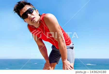 Runner, man and tired with earphones at beach with rest, break or breathing with music in summer sunshine. Person, listening and streaming with subscription with workout, memory and fitness by ocean Runner, man and tired with earphones at beach with rest, break or breathing with music in summer sunshine. Person, listening and streaming with subscription with workout, memory and fitness by ocean 143624180