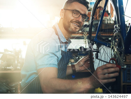 Man, garage and happy as bicycle mechanic with lens flare in startup or small business. Workshop, portrait and smile or confident as handyman with fixing bike at repair or maintenance shop 143624497