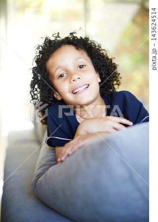 Portrait, smile and child on sofa for relaxation, play and happy for weekend in living room. Young boy, couch and holiday from school for vacation, break and lounge in family home for security Portrait, smile and child on sofa for relaxation, play and happy for weekend in living room. Young boy, couch and holiday from school for vacation, break and lounge in family home for security 143624514