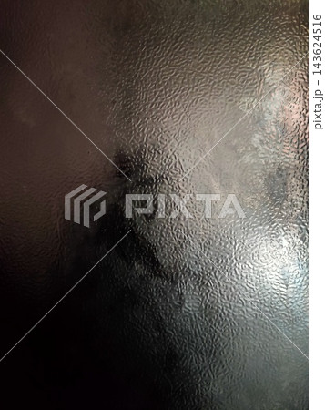 A shadowy figure blurs behind textured glass, creating a mysterious and softly lit visual effect. A shadowy figure blurs behind textured glass, creating a mysterious and softly lit visual effect. 143624516