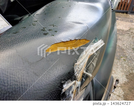Damaged motorcycle seat with torn black cover reveals yellow foam beneath and is patched with clear Damaged motorcycle seat with torn black cover reveals yellow foam beneath and is patched with clear 143624727