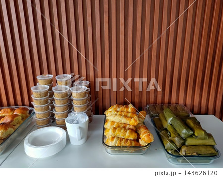 Catering food spread with baked pastries, dessert cups, and traditional banana leaf snacks Catering food spread with baked pastries, dessert cups, and traditional banana leaf snacks 143626120