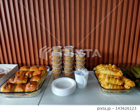 Diverse catering finger food spread on a table with baked rolls and dessert cups Diverse catering finger food spread on a table with baked rolls and dessert cups 143626123