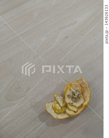 Orange peel and seeds on light wood surface. Discarded remnants of a fruit 143626133
