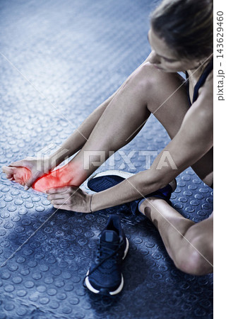 Woman, fitness and foot injury with red glow for accident, bruise or pain in workout or exercise on gym floor. Closeup of female person with sore feet, ache or bone from inflammation for hurt joint 143629460