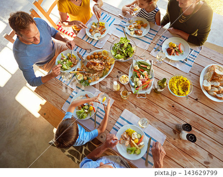 Table, food and top view of family for lunch, supper and eating meal at home together. Celebration, parents and children with dish for bonding, relax and talking for nutrition, health and wellness Table, food and top view of family for lunch, supper and eating meal at home together. Celebration, parents and children with dish for bonding, relax and talking for nutrition, health and wellness 143629799