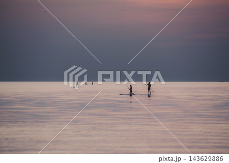 夕日とパプル色の海でSUPを楽しむ人のシルエット 143629886