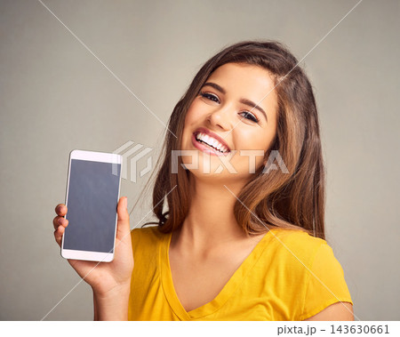 Smile, woman and display of phone screen in studio with mockup space for advertising, marketing or promotion. Portrait, technology and female person presenting cellphone isolated by gray background. Smile, woman and display of phone screen in studio with mockup space for advertising, marketing or promotion. Portrait, technology and female person presenting cellphone isolated by gray background. 143630661