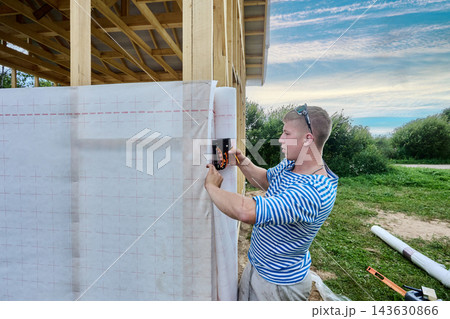 Vapor barrier membrane secured by builder using staple gun on wooden wall frame. Vapor barrier membrane secured by builder using staple gun on wooden wall frame. 143630866