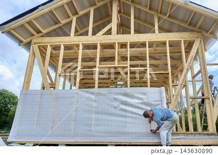 Weather resistant barrier installed by worker with construction stapler on building wall structure. Weather resistant barrier installed by worker with construction stapler on building wall structure. 143630890