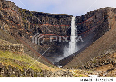 Hengifoss waterfall amid red strata and basalt cliffs in a summer Iceland landscape 143631486
