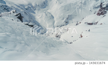 Mount Elbrus snowy steep pass with rugged rocky outcrops and deep powder slopes in bright daylight Mount Elbrus snowy steep pass with rugged rocky outcrops and deep powder slopes in bright daylight 143631674