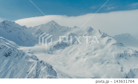 Snow-covered Mount Elbrus ridges and summits in Caucasus Mountains aerial panorama under blue sky Snow-covered Mount Elbrus ridges and summits in Caucasus Mountains aerial panorama under blue sky 143631704