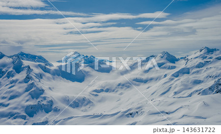 Aerial view of snow-covered Mount Elbrus and surrounding Caucasus peaks under layered cloud sky 143631722